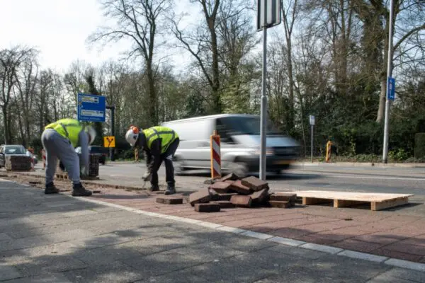 Twee mensen in gele hesjes werken aan een fietspad